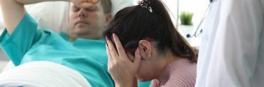 Klinikte yatakta yatan adamın yanında ağlayan bir kız.