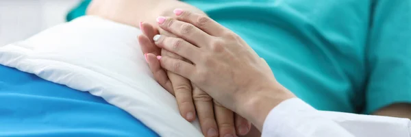Врачи держат за руки пациента, лежащего в палате — стоковое фото