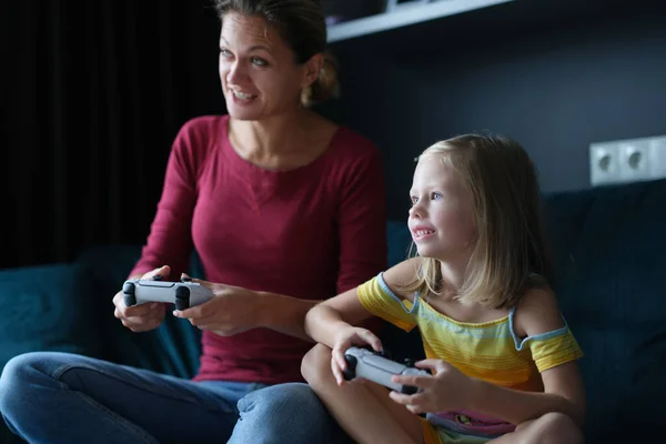 Mamá y su hija tienen joysticks juego y jugar juegos en línea —  Fotos de Stock