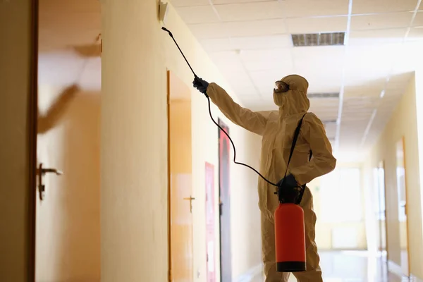Spécialiste en tenue de protection désinfecte les locaux dans le couloir — Photo