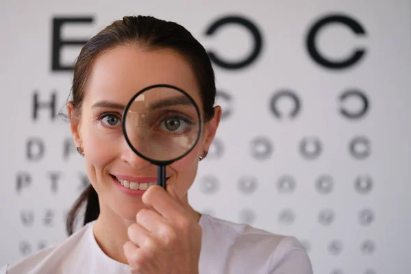 Dokter oogarts kijkt door vergrootglas in oogheelkundige kliniek — Stockfoto