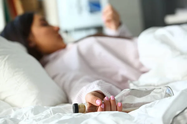 П'яна жінка спить у ліжку і тримає порожню пляшку — стокове фото