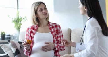 Doctor passes medicine pills to pregnant woman at home