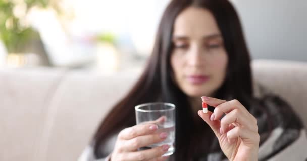 Young woman is holding pill and glass of water — Stock Video