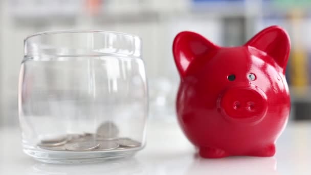 Glass jar piggy bank is filled with coins with piggy bank. — Vídeos de Stock