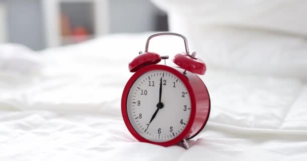 Red alarm clock for seven in morning is on bed — Stock video