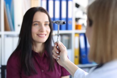 Nörolog doktor klinikte hasta gözlerinin önünde çekiç sürüyor.