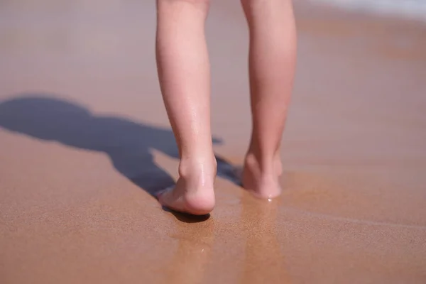 Мокрі голі ноги ходять уздовж пляжу уздовж моря крупним планом — стокове фото