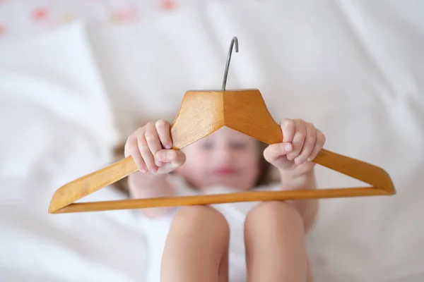 Ragazza bambino tenendo in mano hange in legno primo piano. Scegliere appendiabiti — Foto Stock