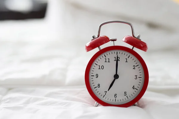 Red alarm clock at 7 oclock on bed — Stok fotoğraf