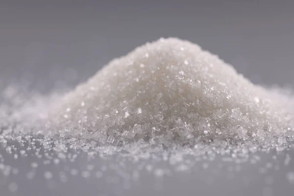 Pilha de cristais de açúcar na superfície cinzenta, amontoado de pó doce para adicionar em pratos — Fotografia de Stock