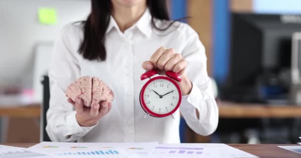 Businessman holding a brain and an alarm clock — Stockvideo