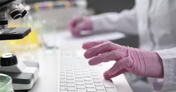 Partial view of scientist typing on computer keyboard in laboratory — Stock Video