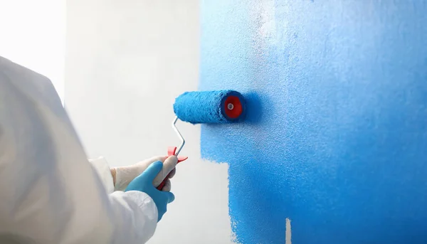 Painter with brush tool covered in blue colour painting wall — Stock fotografie