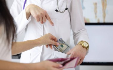Female hand putting money to doctor pocket