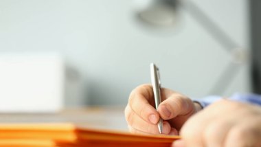 Male hand writing personal address on yellow envelope