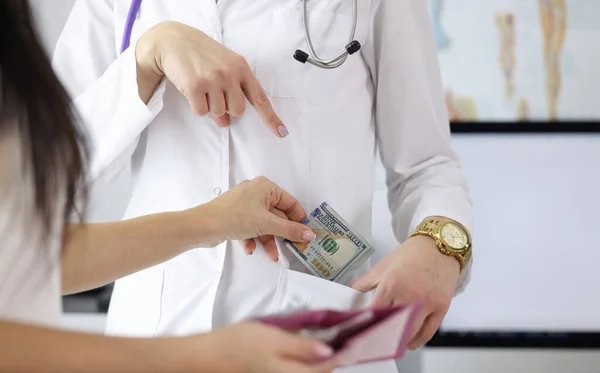 Mão feminina colocando dinheiro no bolso do médico — Fotografia de Stock