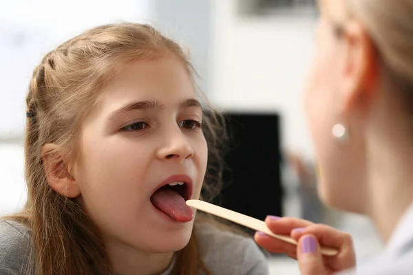 Pediatrician checking girls hurting throat with stick — 스톡 사진