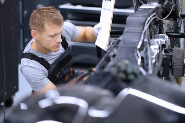 Geconcentreerd mannelijk monteur werk met gereedschap, repareren van beschadigde motorfiets in de werkplaats — Stockfoto