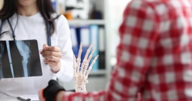 Doctor talks to patient with injured arm and shows x-ray