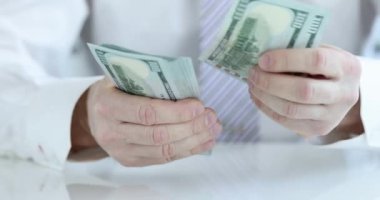İş adamı 100 dolarlık banknotları yakın plan sayar.