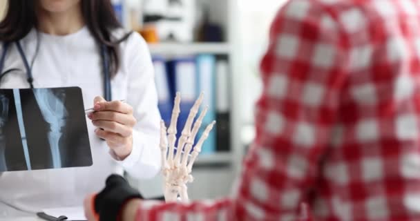 El médico habla con el paciente con el brazo lesionado y muestra rayos X — Vídeo de stock