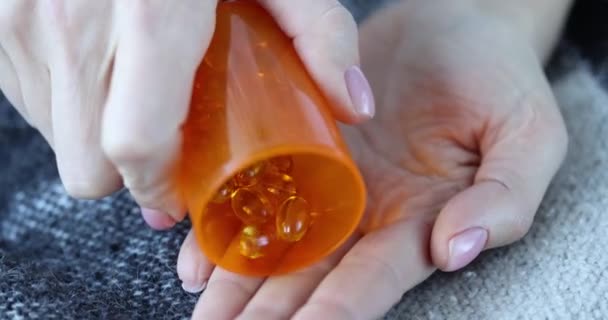 Person pours clear yellow pills into hand closeup — Vídeo de stock