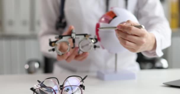 Ophthalmologist shows anatomy of eye and glasses for selection of optics — Video Stock