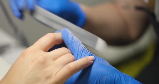 Maestro haciendo manicura con lima de uñas en el salón de belleza primer plano película 4k — Vídeo de stock