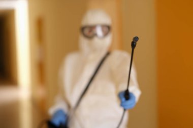 Person in protective suit holding disinfection equipment in hand