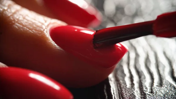 Master painting nails with bright red varnish to client closeup — стоковое фото