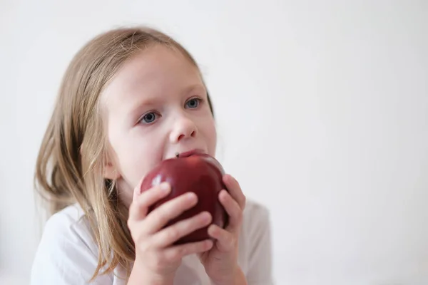 Little girl eating heartily fresh red apple — Fotografia de Stock