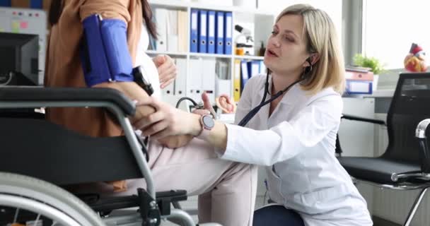 Doctor listens with stethoscope to belly of pregnant woman in wheelchair — Video