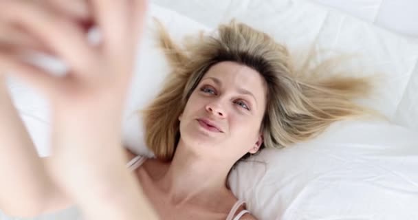 Leende lycklig kvinna liggande på sängen med telefon — Stockvideo