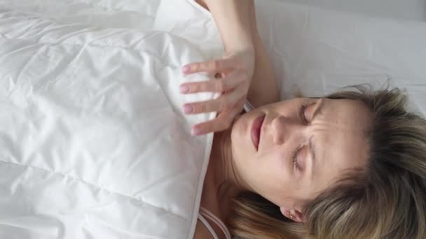 Mujer asustada despertando mira debajo de las sábanas en la cama — Vídeos de Stock