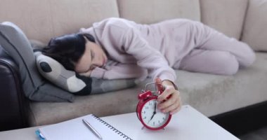 Uyuyan kadın kanepede yatarken alarmı kapatır.