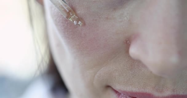 Beautiful woman drips nourishing oil on face — Vídeo de stock