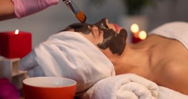 Güzellik salonunda cilt bakımı gören bir kadın. Kozmetik uzmanı yüz derisine maske takıyor