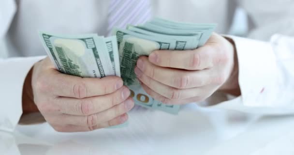 Businessman considers American cash dollars money — стоковое видео