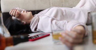 Drunk woman with glass of alcohol lies on floor