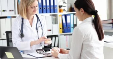 Doktor plastik cerrah kadınlara silikon göğüs implantı gösteriyor.