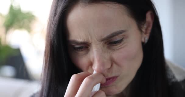 Женщина с насморком держит лекарство в руке и задувается красным носом — стоковое видео
