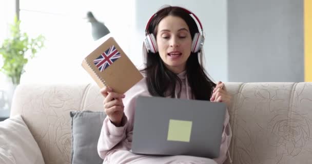 Woman in headphones is learning British English remotely on laptop — Video