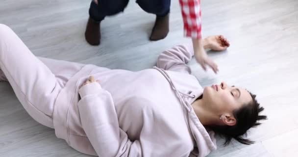 Женщина смотрит на пульс на сонной артерии и делает косвенный массаж сердца для бессознательного мужчины 4К фильм — стоковое видео