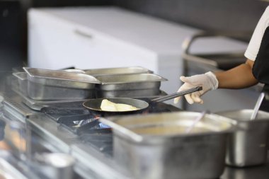 Aşçı mutfakta tavada omlet hazırlar, kafelerde ve restoranlarda yemek pişirir.