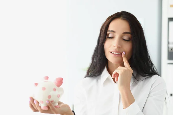 Woman hold piggybank, think of better way to use money, saving up for future — Zdjęcie stockowe