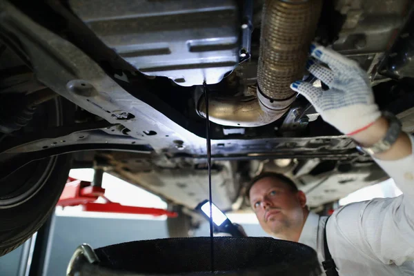 Tamirci araba altında yağ değiştiriyor, araba bakım servisi, yağ damlatıyor. — Stok fotoğraf