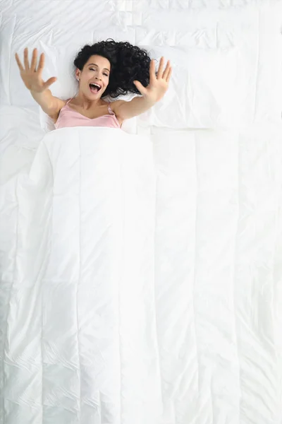 Pretty woman laying on white bedding, wake up well rested in morning, stretching after sleep — Stok fotoğraf