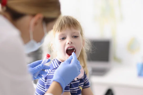 Asystent laboratoryjny w kombinezonie ochronnym pobiera wymaz z gardła dziecka, zabieg w domu — Zdjęcie stockowe