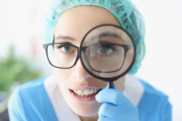 戴眼镜的医生看穿放大镜，实习生在诊所做检查 — 图库照片